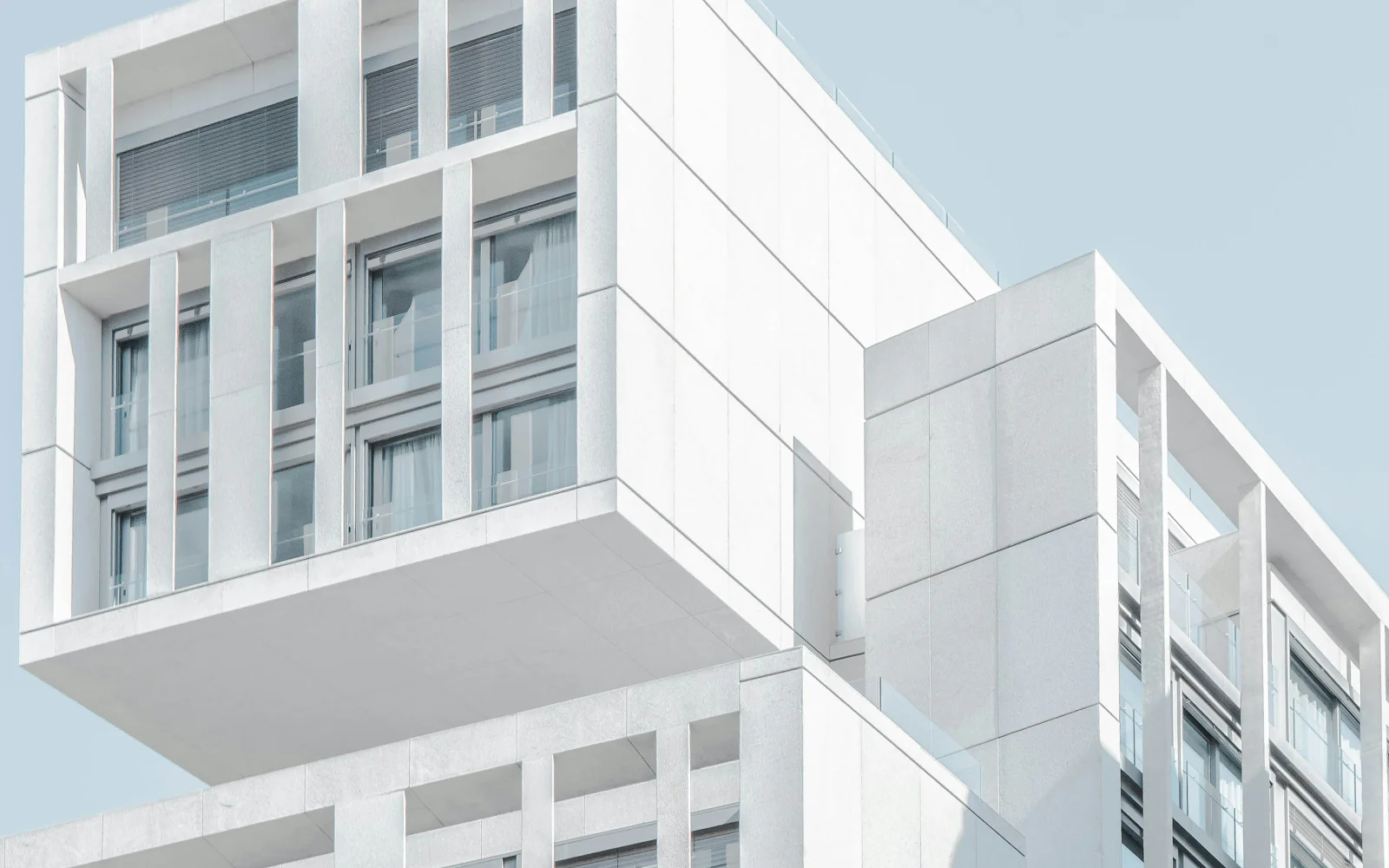 White cantilevered apartment buildings against a pale blue sky.