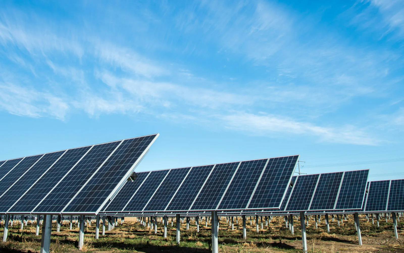 Rows of solar panels beneath a bright blue sky.