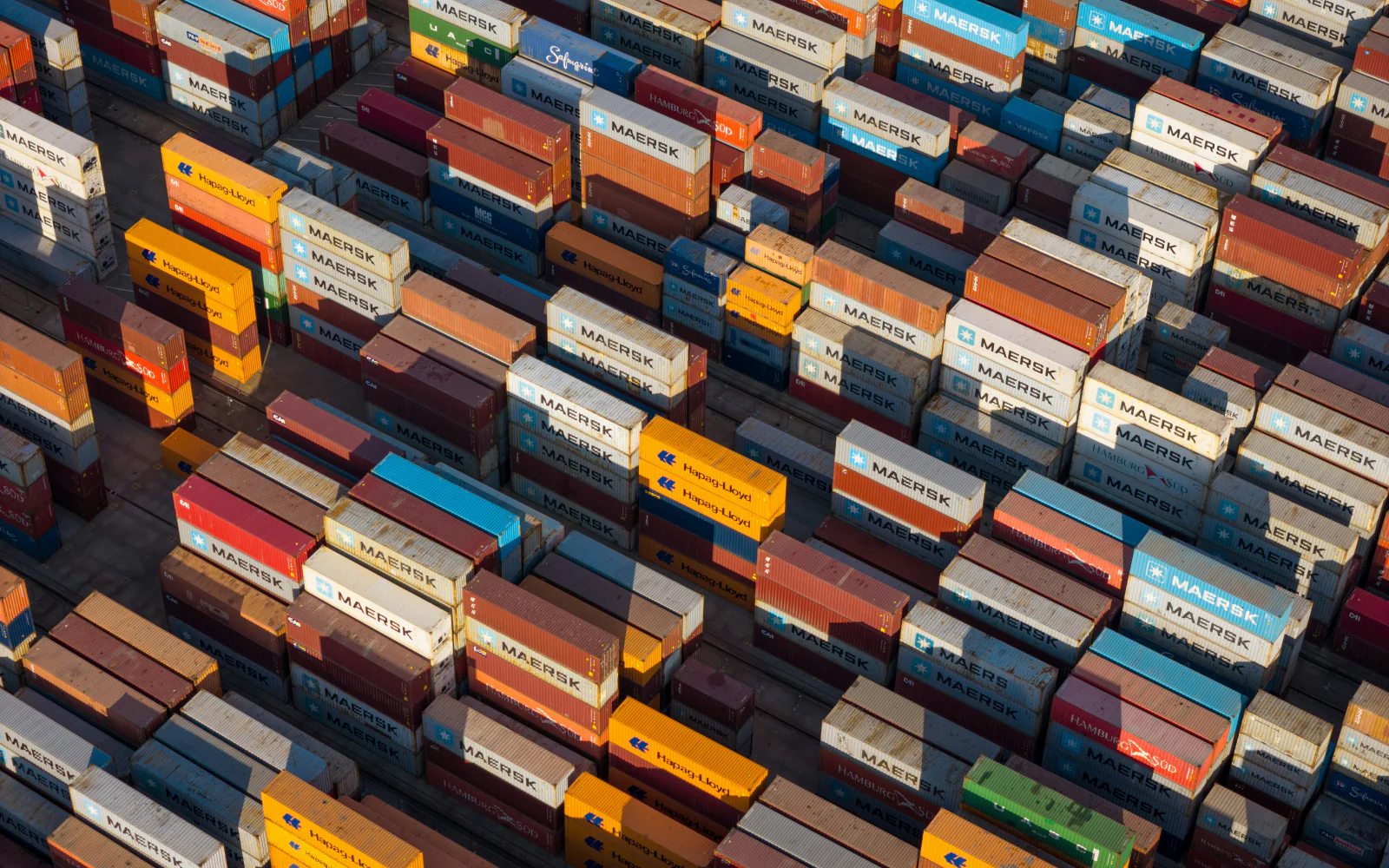 Colorful shipping containers stacked in rows at a freight terminal.